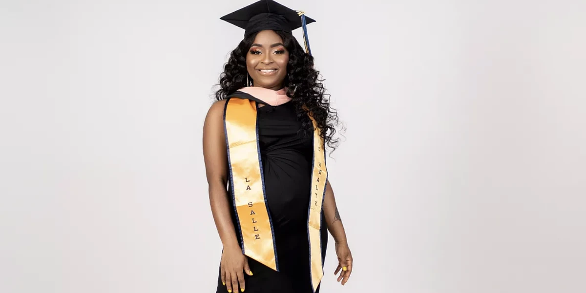 A woman posing for a photo in graduation garb